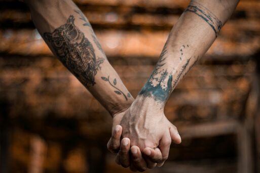 Two tattooed arms clasp hands. 