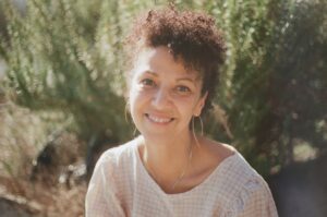 Portrait of poet Rosa Castellano smiling with a plant behind her