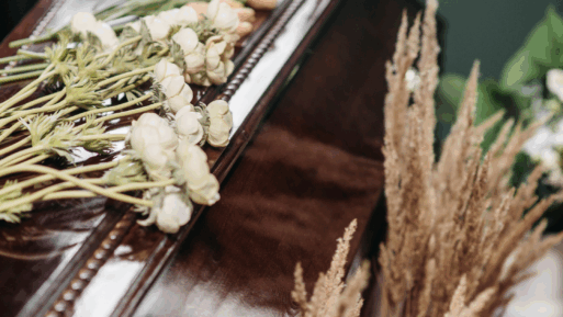 Close-up of white flowers and wheat on a casket for a cremation ceremony.