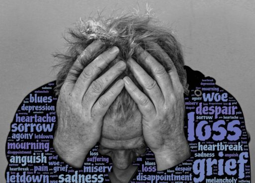 In a black-and-white filtered photo, an older man is holding his head in his hands, fingers laced through his hair. Superimposed on his black shirt are various synonyms for grief