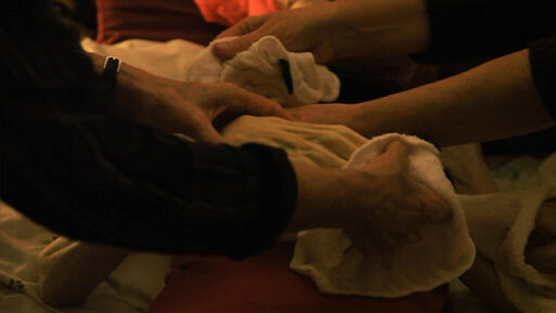 A dimly-lit photograph of hands gently cleaning something with cloths