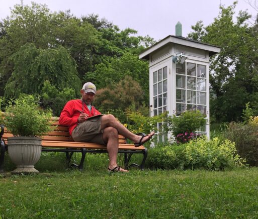 A photo of a man seated on a bench near the wind phone booth in Japan. 