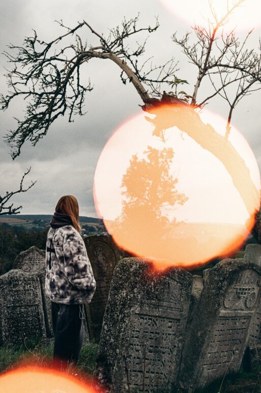 Woman laughing in a cemetery looking at what appears to be a spirit.