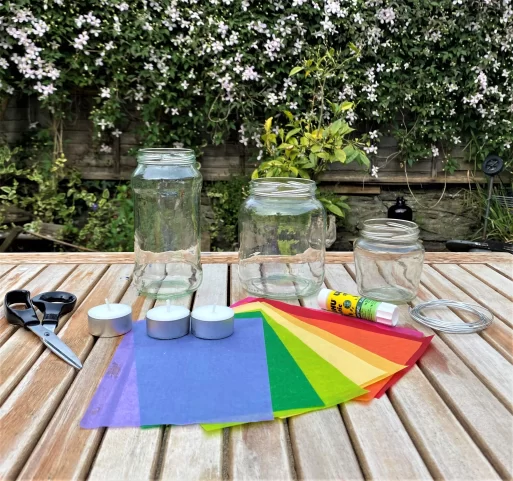 Colorful tissue paper, glass mason jars, scissors, glue, and tea light candles for a lantern craft project