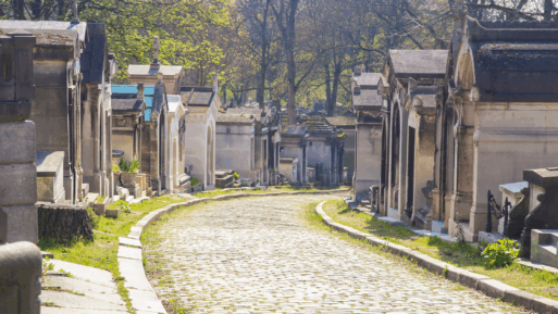 Historic tombs line a cobbled pathway through verdant grass and trees