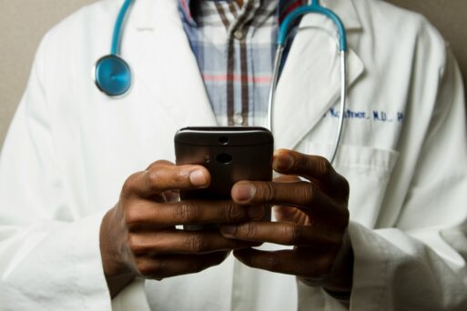 doctor wearing lab coat and stethoscope holding smart phone
