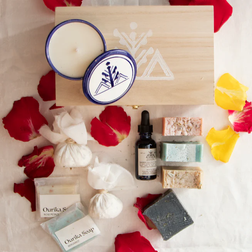 a self-care kit with soap bars, organic face and body oil, signature bath salts, and a scented candle in a pretty ceramic jar