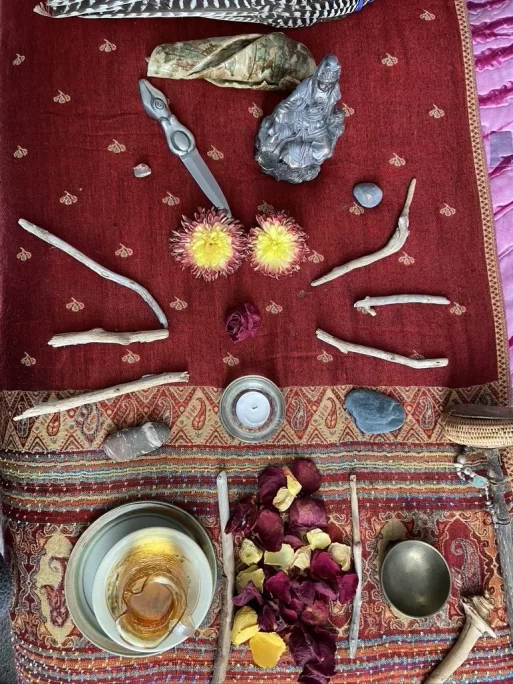 Sacred items, including flower petals, a bowl of water, and items with symbolic meaning are placed on a table as an altar to the dead.