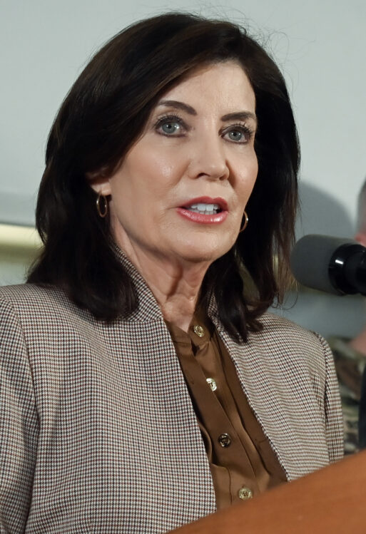 Governor Kathy Hochul, a middle-aged brunette, is dressed professionally as she speaks at a podium.