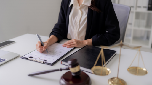 A woman signs official documents at a desk with legal paraphernalia in a stock photo