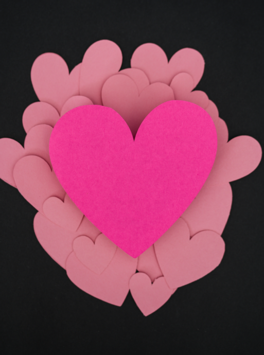 a pile of pink construction paper cut into hearts as invites for a celebration of life event