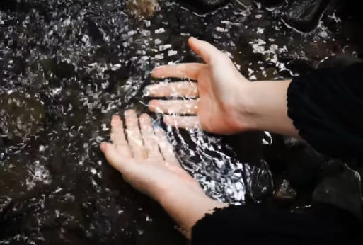 Screenshot from the video of Caoine by RÓIS of hands in water