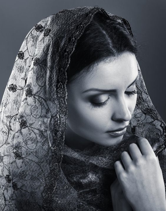 beautiful sad woman covered by transparent fabric on dark background ...