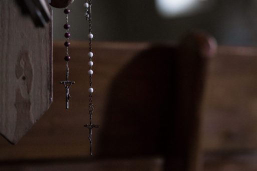 Rosary beads hang from a church pew