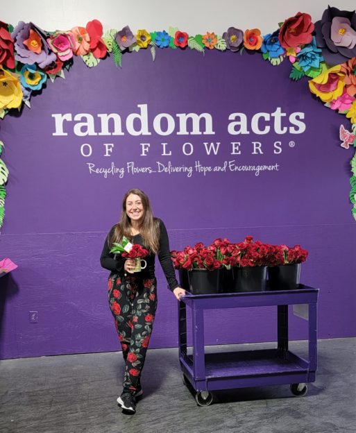 Steffani speaks in front of a banner for Random Acts of Flowers