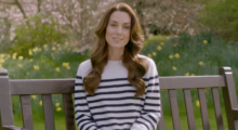 Kate Middleton, the Princess of Wales, sits on a sunny park bench wearing a cream-and-black stripped sweater as she issues a statement regarding her recent surprising cancer diagnosis
