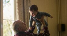 A grandfather joyfully tosses a baby into the air