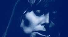 The cover art of Joni Mitchell's album, "Blue," which is a close-up photo of the young folk artists's face singing into a microphone, all in blue tones