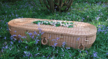 Environmentally friendly coffin sitting on grassy field.